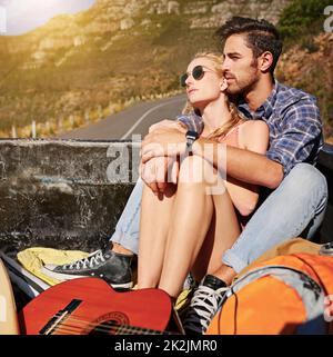 Leben, die nicht an einem Ort gelebt werden sollten. Aufnahme eines jungen Paares, das sich auf einer Autoreise auf der Rückseite eines Pickups entspannt. Stockfoto