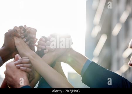 Waren immer besser zusammen. Aufnahme einer Gruppe von nicht erkennbaren Geschäftsleuten, die sich vor einem Stadthintergrund die Hände hielten. Stockfoto