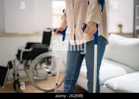 Bein Mit Krücken In Der Nähe Des Rollstuhls Verletzen Stockfoto