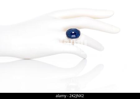 Blauer Saphirring auf Plastikfiguren weibliche Hand. Kollektion von natürlichen Edelsteinen Accessoires. Studioaufnahme Stockfoto