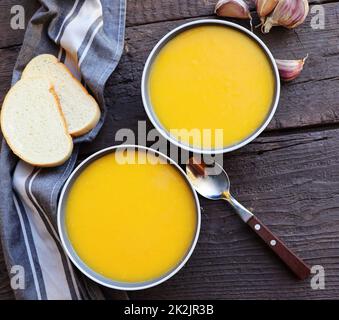 Frische Kürbis-Sahnesuppe zum Herbstessen auf rustikalem Tisch Stockfoto