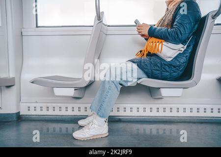 Eine ältere Frau sendet eine Nachricht mit einem Mobiltelefon im Zug Stockfoto