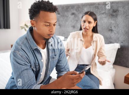 Ein Paar oder ein schwarzer Mann ignorieren frustrierte Frauen, die in sozialen Medien, im Internet oder im Internet auf dem Bett telefonieren. Junge schwarze Menschen aus, wütend und aufgeregt Stockfoto