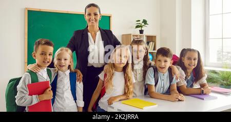 Porträt einer jungen intelligenten Lehrerin mit ihren kleinen Schülern der Grundschule. Stockfoto