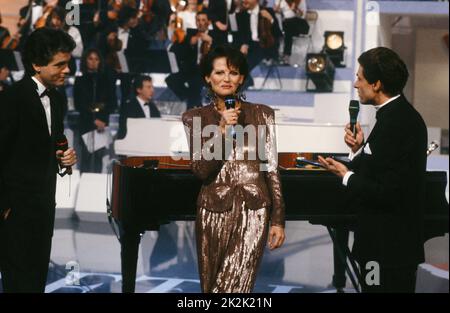 Telethon 1990 Charity-Abend. Die Sponsorin des Abends, die Schauspielerin Claudia Cardinale, und die Moderatoren Claude Sérillon (l.) und Gérard Holtz (r.). 8. Dezember 1990 Stockfoto