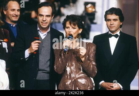 Telethon 1990 Charity-Abend. Der Sponsor des Abends, die Schauspielerin Claudia Cardinale, der Moderator Claude Sérillon (r.) und Frédéric Mitterrand (l.). 8. Dezember 1990 Stockfoto