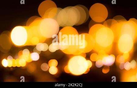 Verschwommener gelber Bokeh-Hintergrund. Abstrakter Hintergrund von Stadtlicht verwischen. Warmes Licht mit wunderschönem rundem Bokeh. Orangefarbenes Licht in der Nacht. Die Straßenlaterne verschwommene Lichter in der Stadt bei Nacht. Stockfoto