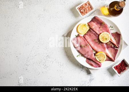 Frische Tintenfische Tintenfische oder Tintenfische für gekochte Speisen. Frischer roher Tintenfisch. Roher Tintenfisch mit Zitrone. Draufsicht und Kopierbereich für Ihren Text. Stockfoto