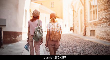 Zwei Frauen mit Rucksäcken gehen im alten Tallinn, Estland. Stockfoto