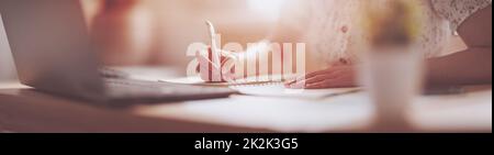 Frau, die im Büro in einem Notizbuch schreibt Stockfoto