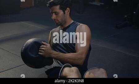 Muskulärer Sportler, der Bauchübungen mit einem Medizinball macht Stockfoto