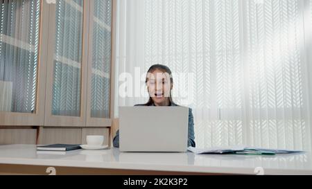 Glückliche Geschäftsfrau war begeistert und überraschte die Arbeit an einem weißen Büroschreibtisch mit pc-Laptop, der Papierdokumente auswarf Stockfoto