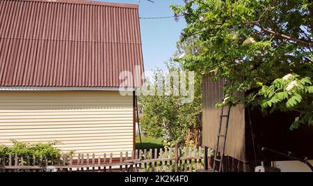 Modernes ländliches authentisches Haus mit Abstellgleis und Nebengebäuden im Hinterhof, das Konzept des Sommerlebens auf dem Land Stockfoto