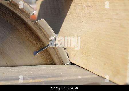 Ein Stück Holz liegt am Sägeblatt einer Kreissäge an Stockfoto
