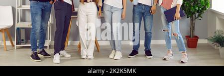 Gruppe junger Männer und Frauen in lässiger Kleidung und Turnschuhen, die im Büro oder Klassenzimmer stehen Stockfoto