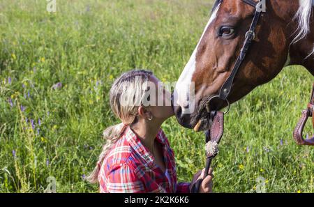 Ein junges Mädchen küsst ihr Pferd Stockfoto