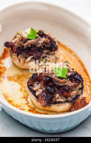 Champignongs gefüllt mit Zwiebeln und trockenen Tomaten Stockfoto