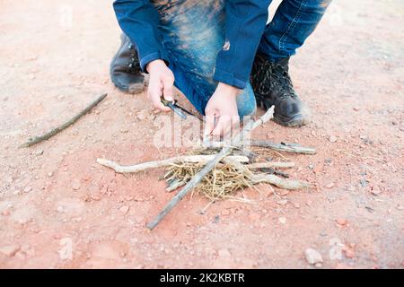 Ein Feuer mit einem Feuerstahl, Überlebens- und Abenteuerausrüstung, Outdoor-Fähigkeiten, Mann, der ein Lagerfeuer macht Stockfoto