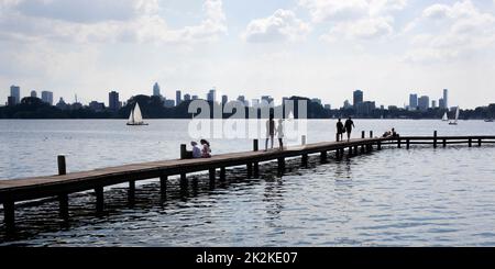 Die Menschen chillen auf einer Anlegestelle in der Kralingse Plas mit der Skyline von Rotterdam im Hintergrund Stockfoto