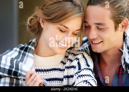 Gemütlich für den Winter. Ein junges Paar, das in eine Decke gehüllt wurde. Stockfoto