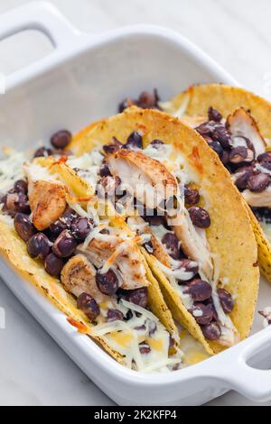 Tacos gefüllt mit gegrilltem Hähnchenfleisch, roten Bohnen und geriebenem Käse Stockfoto