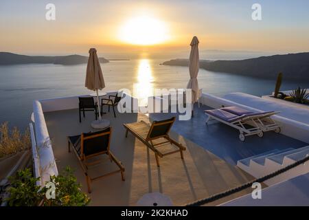 Sonnenliegen auf der Terrasse im Dorf Imerovigli mit herrlichem Blick auf den Sonnenuntergang über der Caldera in Santorin Stockfoto