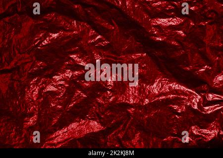 Zerknitterte Hintergrundstruktur aus roter Folie mit Lichtreflexion Stockfoto