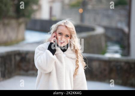 Attraktive blonde Frau in einem stilvollen Wintermantel Stockfoto