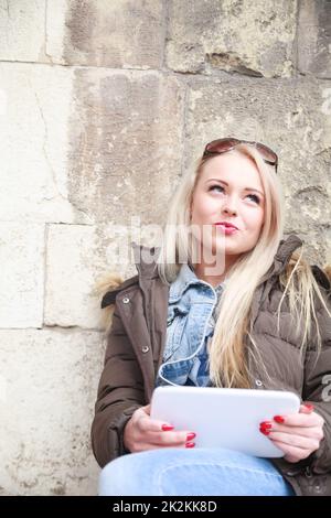 Süße charismatische junge Frau, die mit einem Tablet-pc Tagträumt Stockfoto