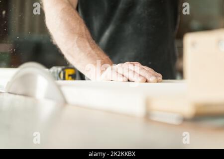 Die Hand eines Zimmermanns mit einer Gehrungssäge Stockfoto