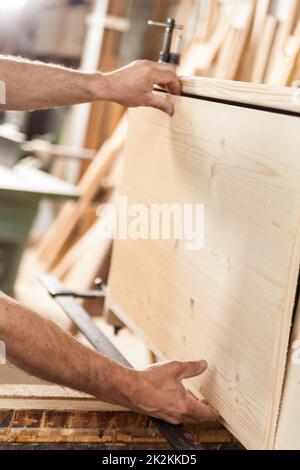 Holzarbeiterhände mit Holzbrett Stockfoto