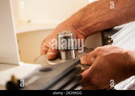 Die Hand eines Holzarbeiters, der einen Fräser aufstellt Stockfoto