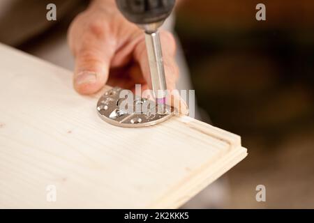 Konzentrieren Sie sich auf einen Schraubendreherbit, der eine Holzplatte verschraubt Stockfoto