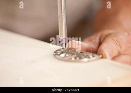 Konzentrieren Sie sich auf einen Schraubendreherbit, der eine Holzplatte verschraubt Stockfoto