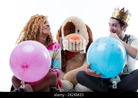 Junge Frau mit einem Mann, der Partyballons bläst Stockfoto