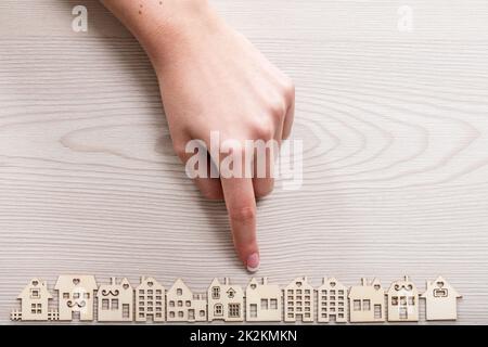 Hand, ein Haus unter den anderen Mini Figuren in einem micro Holz- dorf Stockfoto