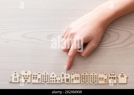 Hand, ein Haus unter den anderen Mini Figuren in einem micro Holz- dorf Stockfoto