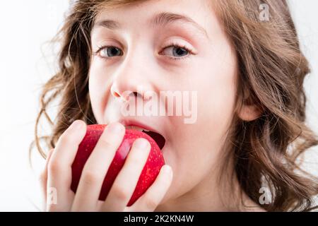 Mädchen isst roten Apfel auf weißem Hintergrund Stockfoto