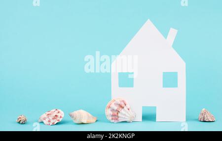 Weißes Haus auf blauem Hintergrund mit Muscheln, buchen ein Apartment, Hotel oder Lounge für Urlaub, Urlaub im Sommer am Strand, kopieren Sie Platz für Text Stockfoto