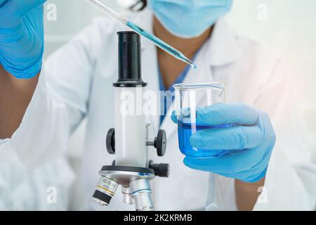 Asian Wissenschaftler Biochemiker oder Mikrobiologe arbeiten Forschung mit einem Mikroskop im Labor. Zum Schutz vor Ausbruch Coronavirus Covid19, Bakterien und Keimen. Stockfoto