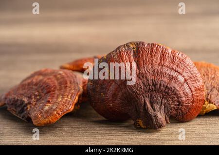 Getrockneter Lingzhi-Pilz auf hölzernem Hintergrund, gesundes Kräuterfutter. Stockfoto