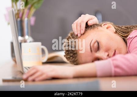 Müde, attraktive junge Frau, die auf einem Tisch schläft Stockfoto