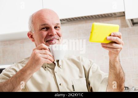 Grinsender Mann mit digitalem Lesegerät und Becher Stockfoto