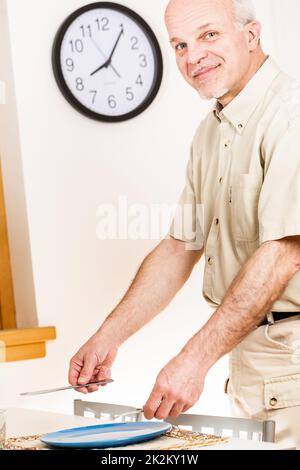 Ein Mann bereitet die Tischeinstellung für die Mahlzeit vor Stockfoto