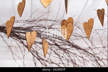 Ornamente in Form von Herzen. Hölzerne Ornamente auf den Ästen. Herzen aus Holz geschnitten. Herbstthema. Stockfoto