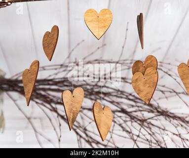 Ornamente in Form von Herzen. Hölzerne Ornamente auf den Ästen. Herzen aus Holz geschnitten. Herbstthema. Stockfoto