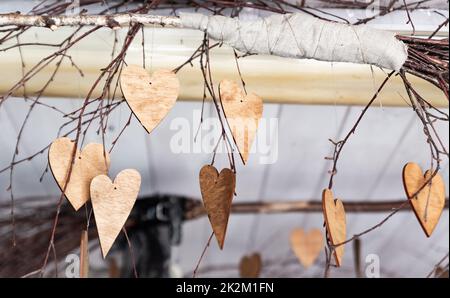 Ornamente in Form von Herzen. Hölzerne Ornamente auf den Ästen. Herzen aus Holz geschnitten. Herbstthema. Stockfoto