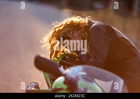 Eine Frau, die ihr Motorrad zum Laufen bereitete Stockfoto