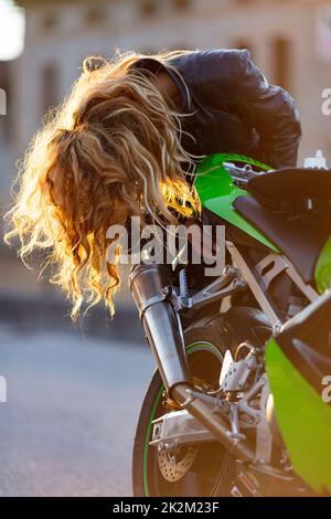 Eine Frau, die ihr Motorrad zum Laufen bereitete Stockfoto