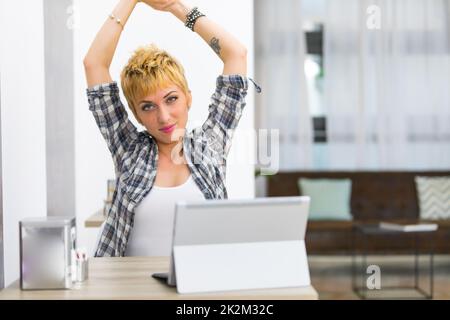 Junge Frau, die sich zu Hause dehnt Stockfoto